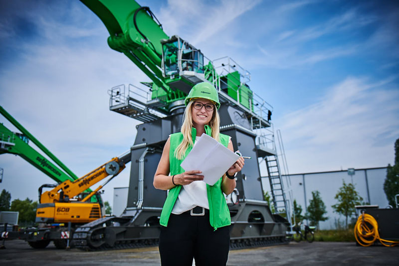 Sennebogen Mitarbeiterin vor einem Krahn